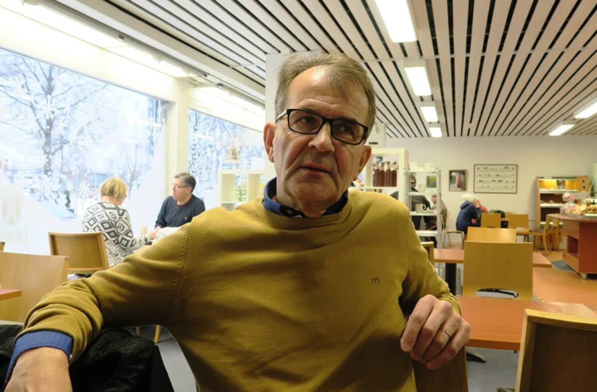 Mies istuu kahvilassa