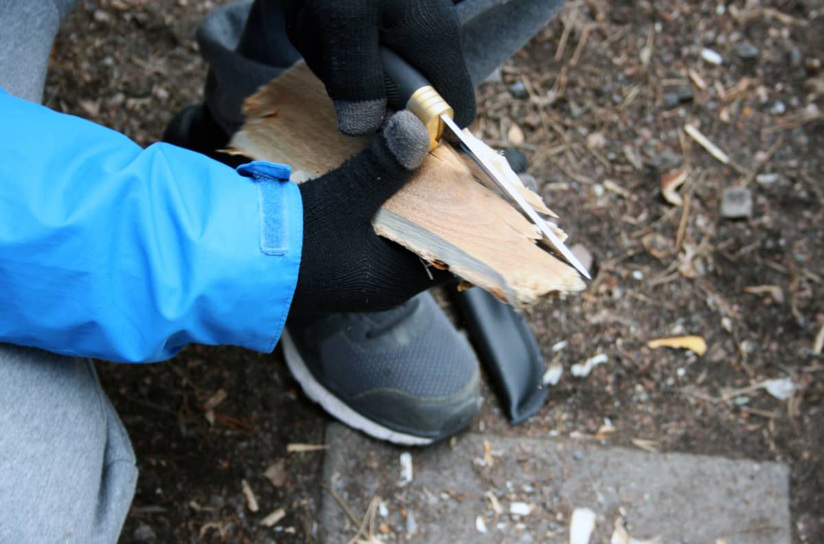 Puukko ja halko käsissä.