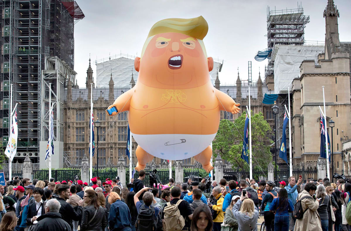 Mielenosoittajat lennättävät trump -ilmapalloa.