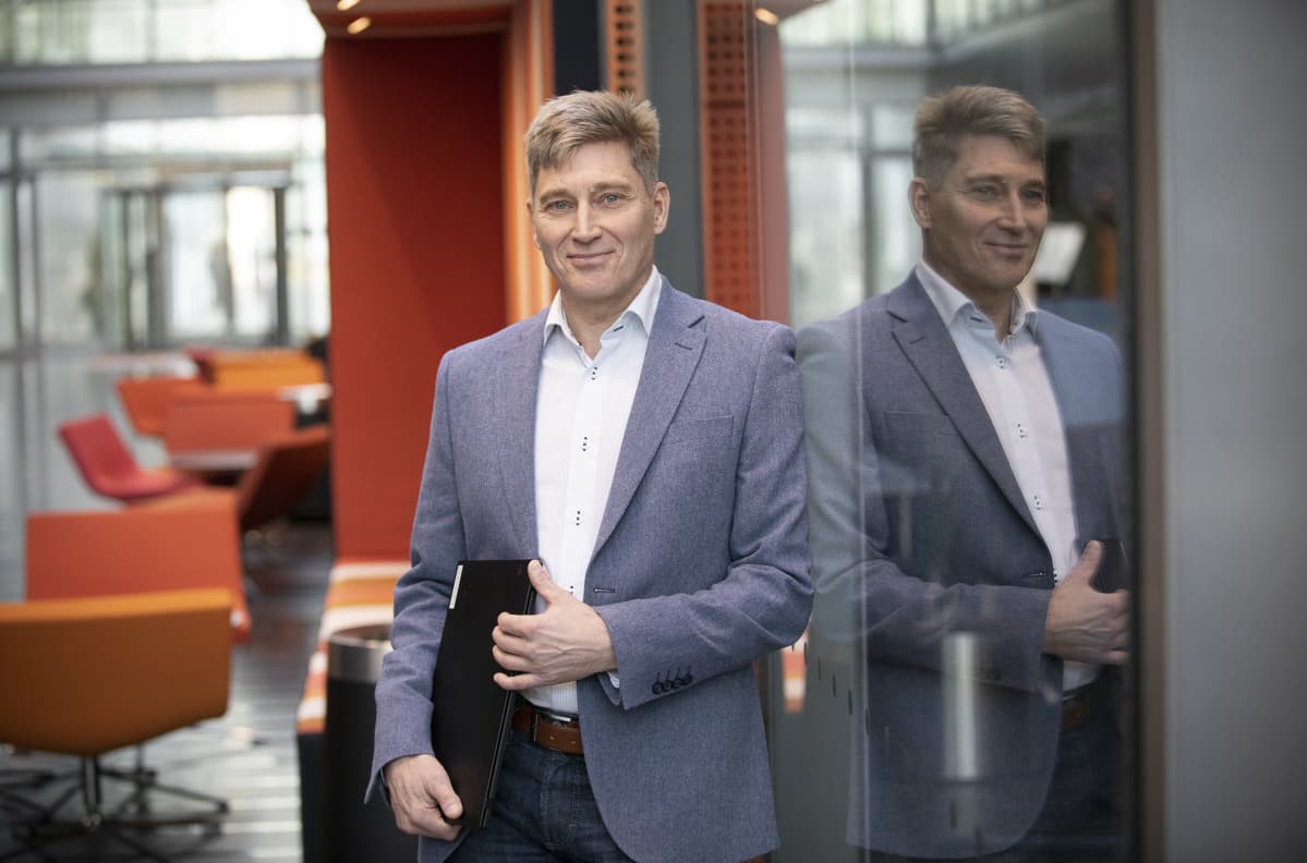 Johtava asiantuntija Timo Tuominen seisoo Finanssialan toimistorakennuksen vastaanottoaulassa kannettava tietokone käsissään.