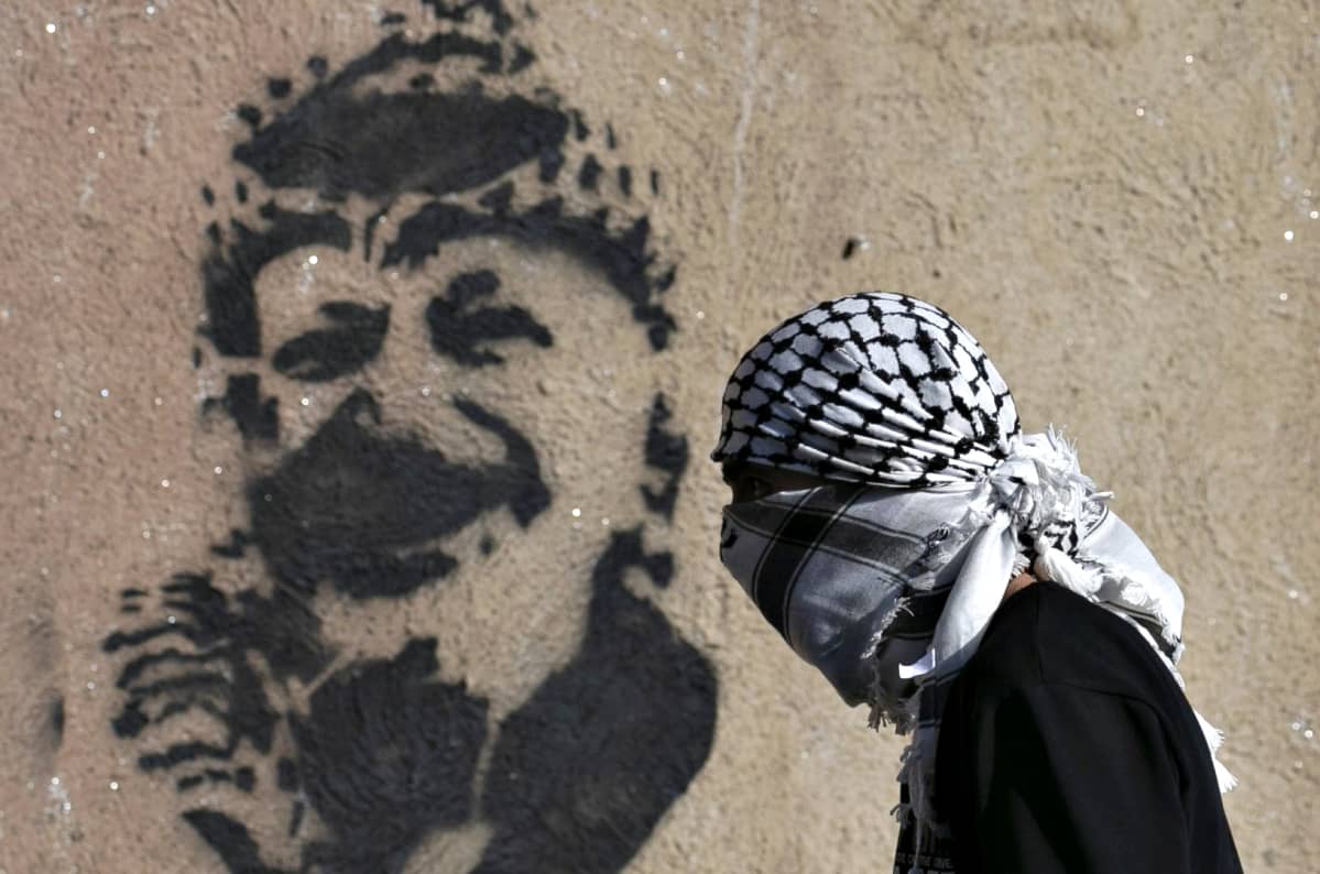 Palestiinalainen mielenosoittaja kävelee Jasser Arafatin graffitin ohi 7. helmikuuta.