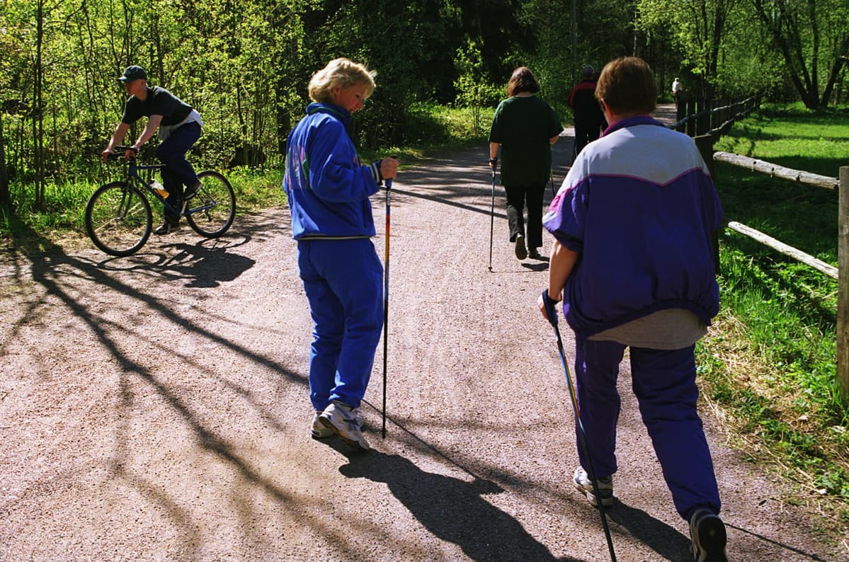 Ihmisiä sauvakävelyllä.