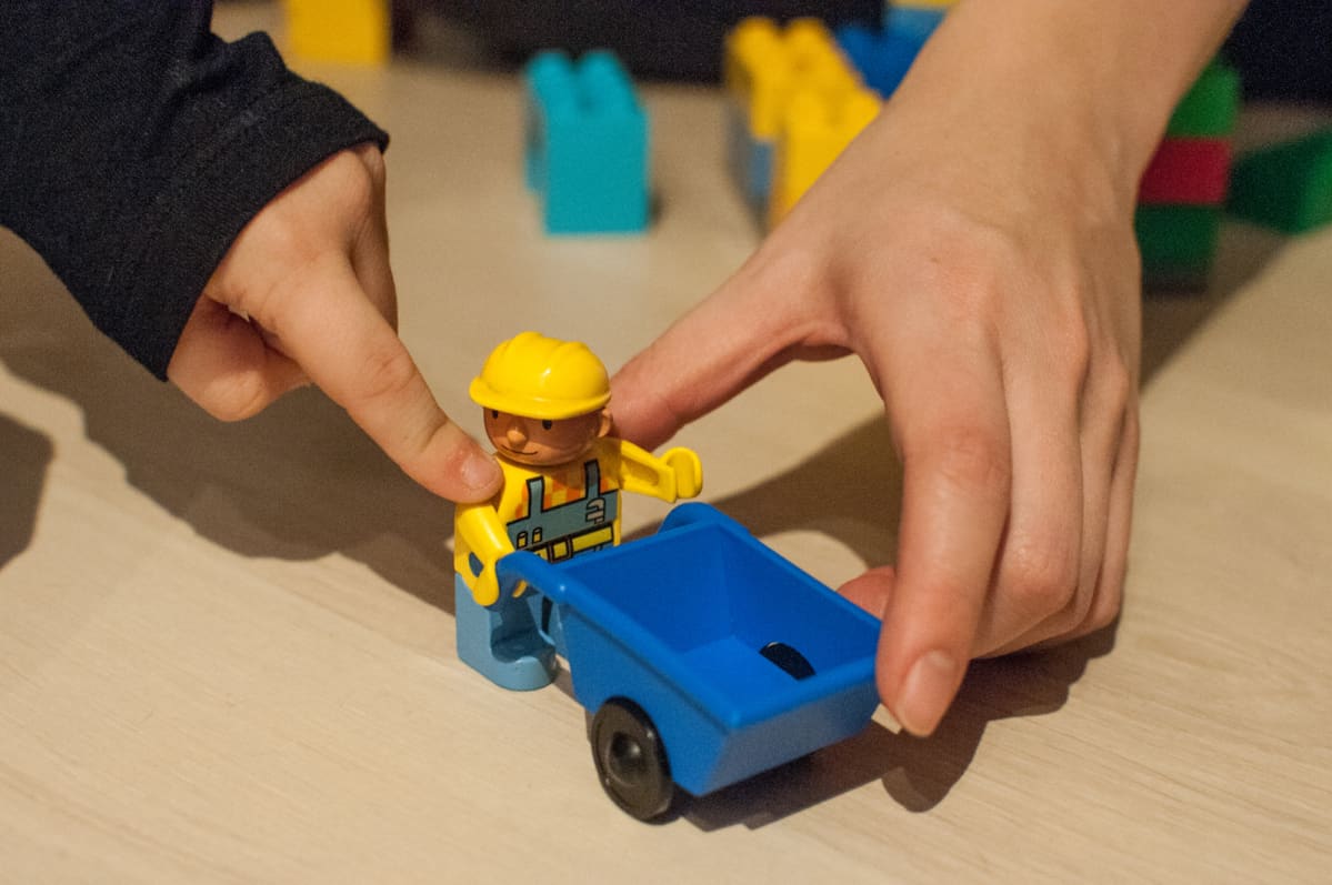 Lapsi ja aikuinen leikkii legoilla.