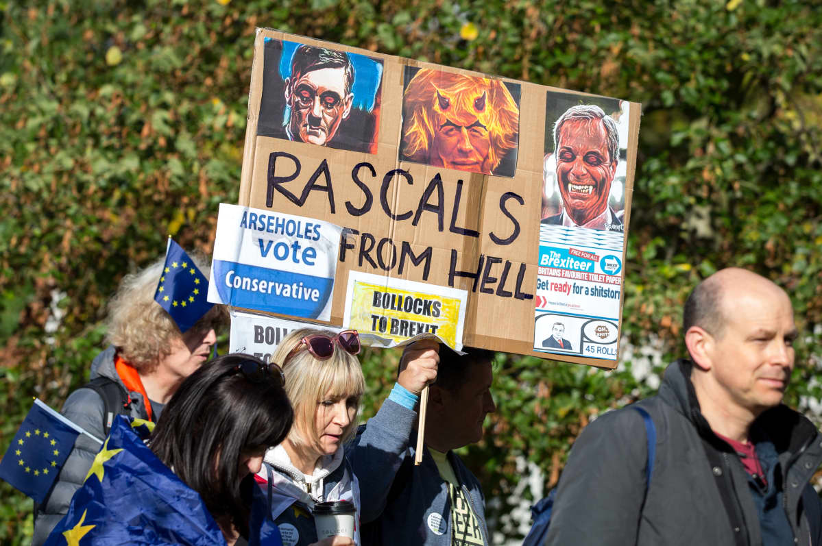 Mielenosoittajat kantavat Boris Johnsonia, Nigel Faragea ja Jacob Rees-Moggia pilkkaavaa kylttiä.