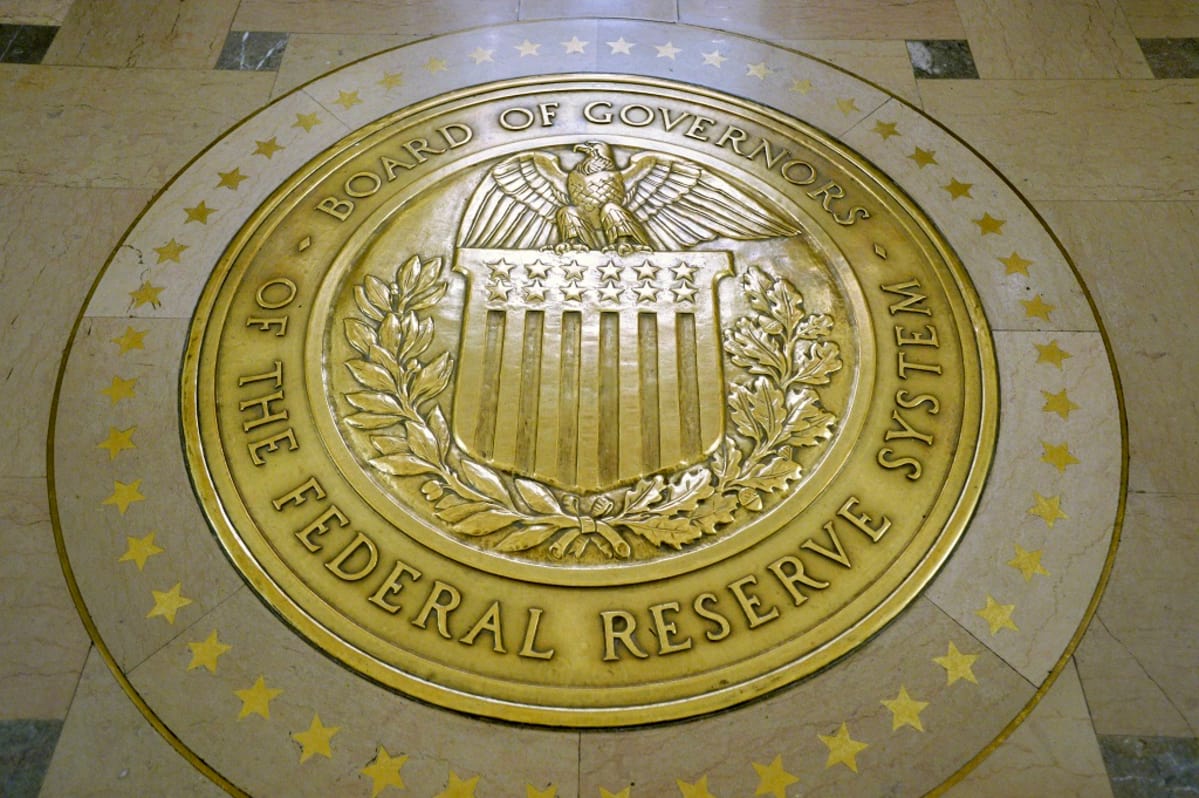 Yhdysvaltain keskuspankin Federal Reserven hallituksen keltainen vaakunakuvio lattiassa. Sinetin reunalla lukee versaaleilla: Board of Governors. The Federal Reserve System. Keskellä on kuva kotkasta, joka istuu Yhdysvaltain lipun koristaman vaakunakilven päällä.