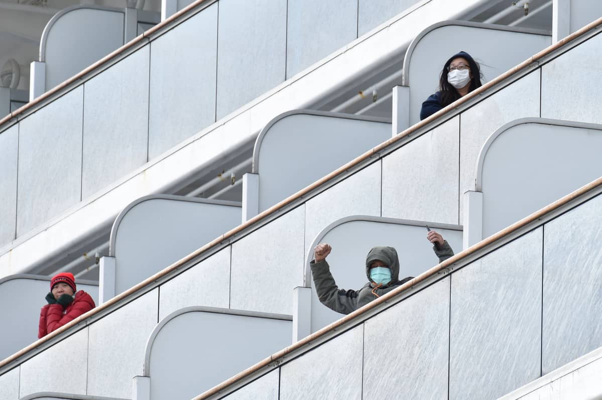 Diamond Princess -aluksella karanteenissa olevat matkustajat vilkuttivat medialle 6. helmikuuta.