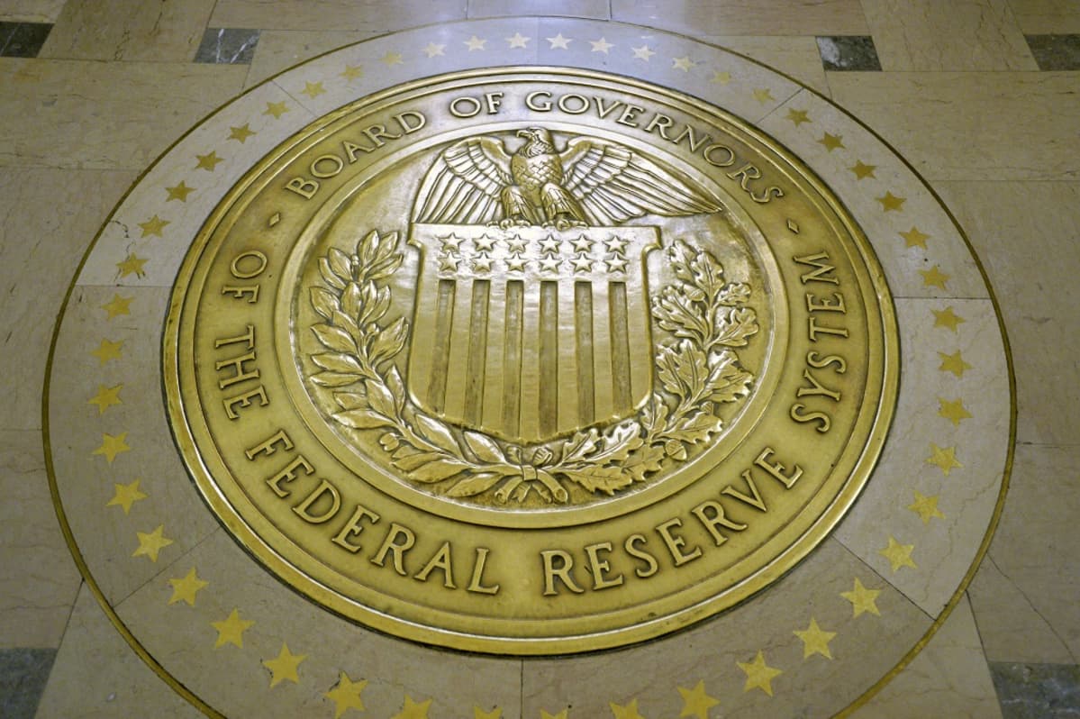 Yhdysvaltain keskuspankin Federal Reserven hallituksen keltainen vaakunakuvio lattiassa. Sinetin reunalla lukee versaaleilla: Board of Governors. The Federal Reserve System. Keskellä on kuva kotkasta, joka istuu Yhdysvaltain lipun koristaman vaakunakilven päällä.