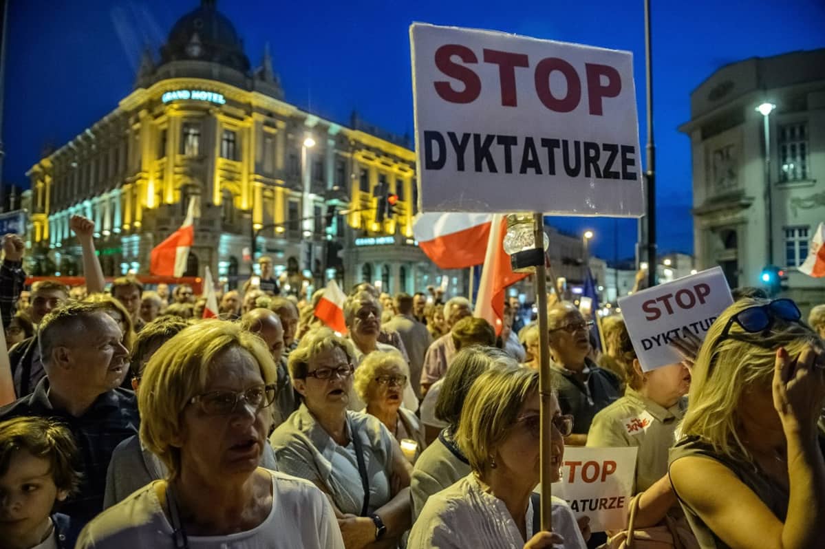 Hallituksen vastaiset mielenosoittajat kantavat käsissään kylttejä Puolassa.