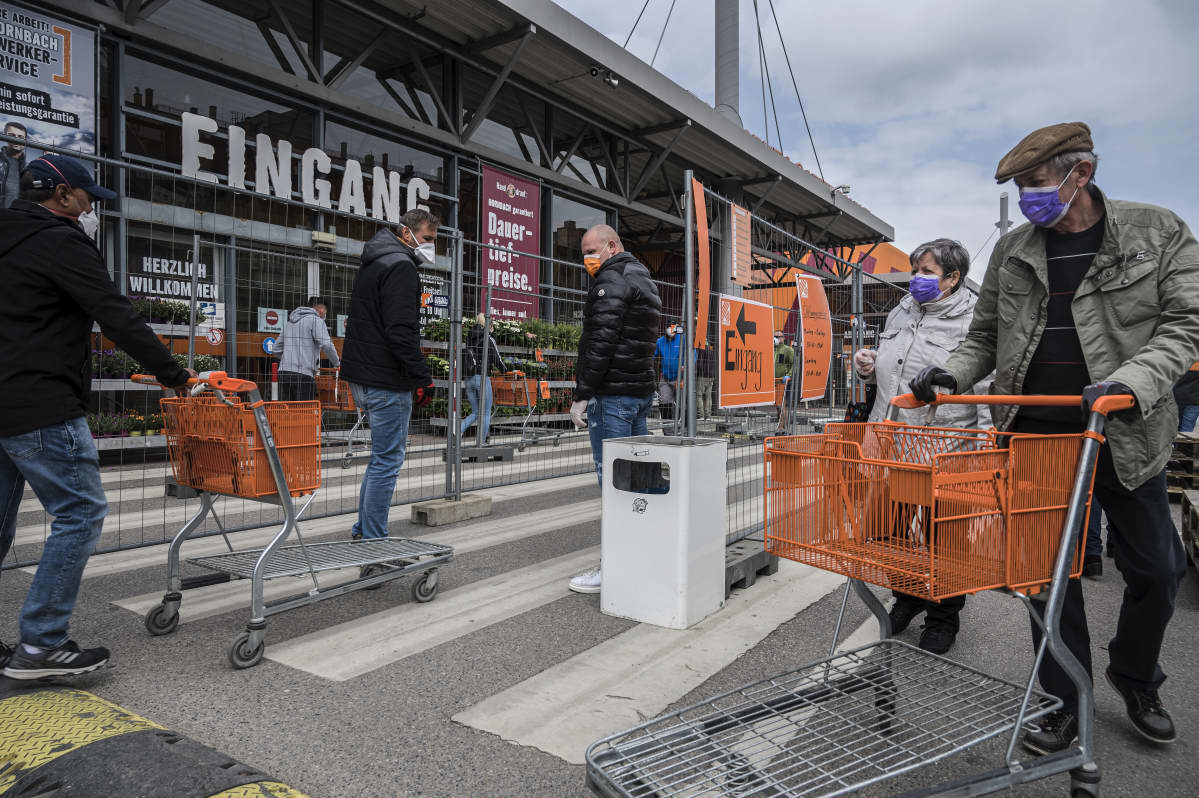 Kasvosuojin varustautuneita asiakkaita jonottamassa rautakauppaan