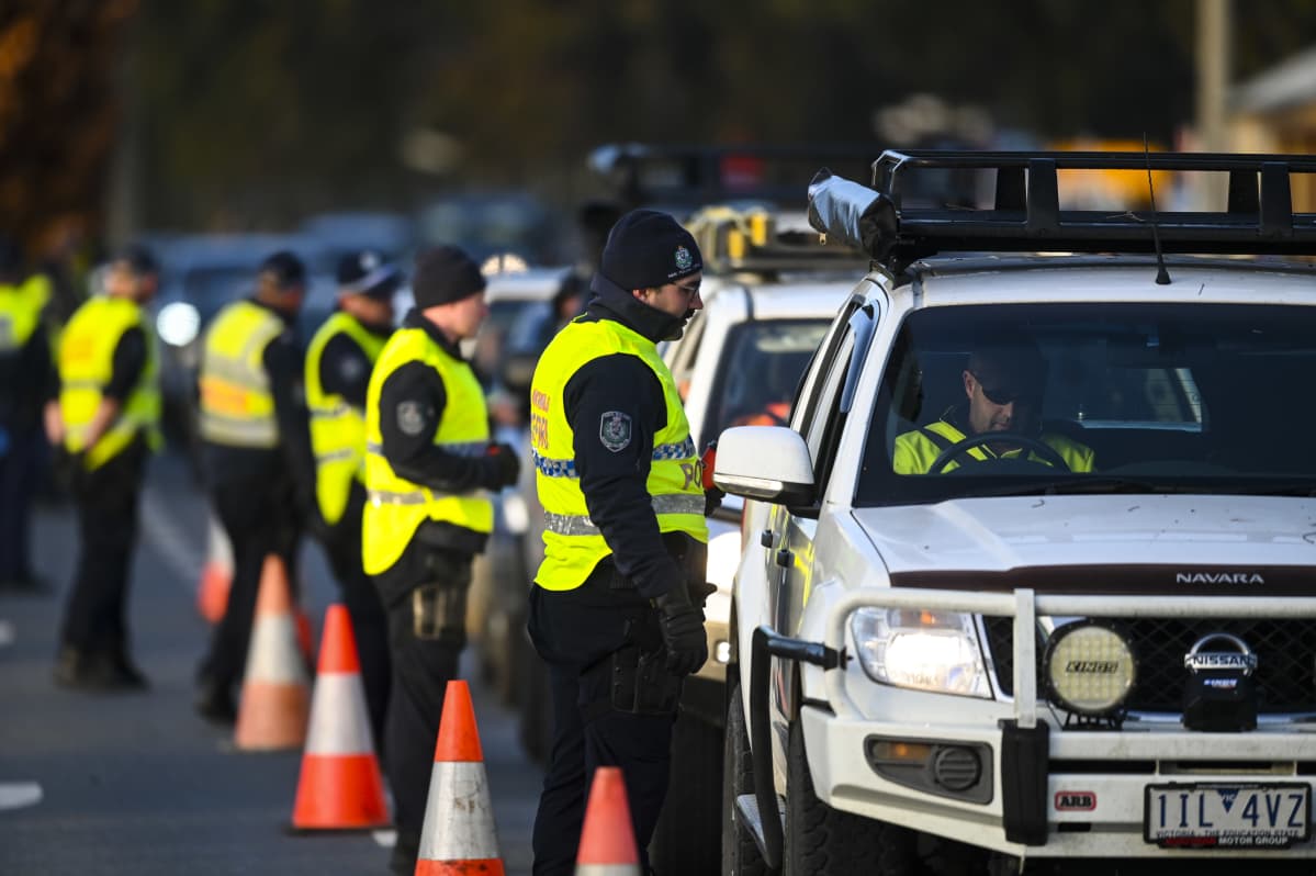 Pitkä rivi poliiseja autojonon vieressä