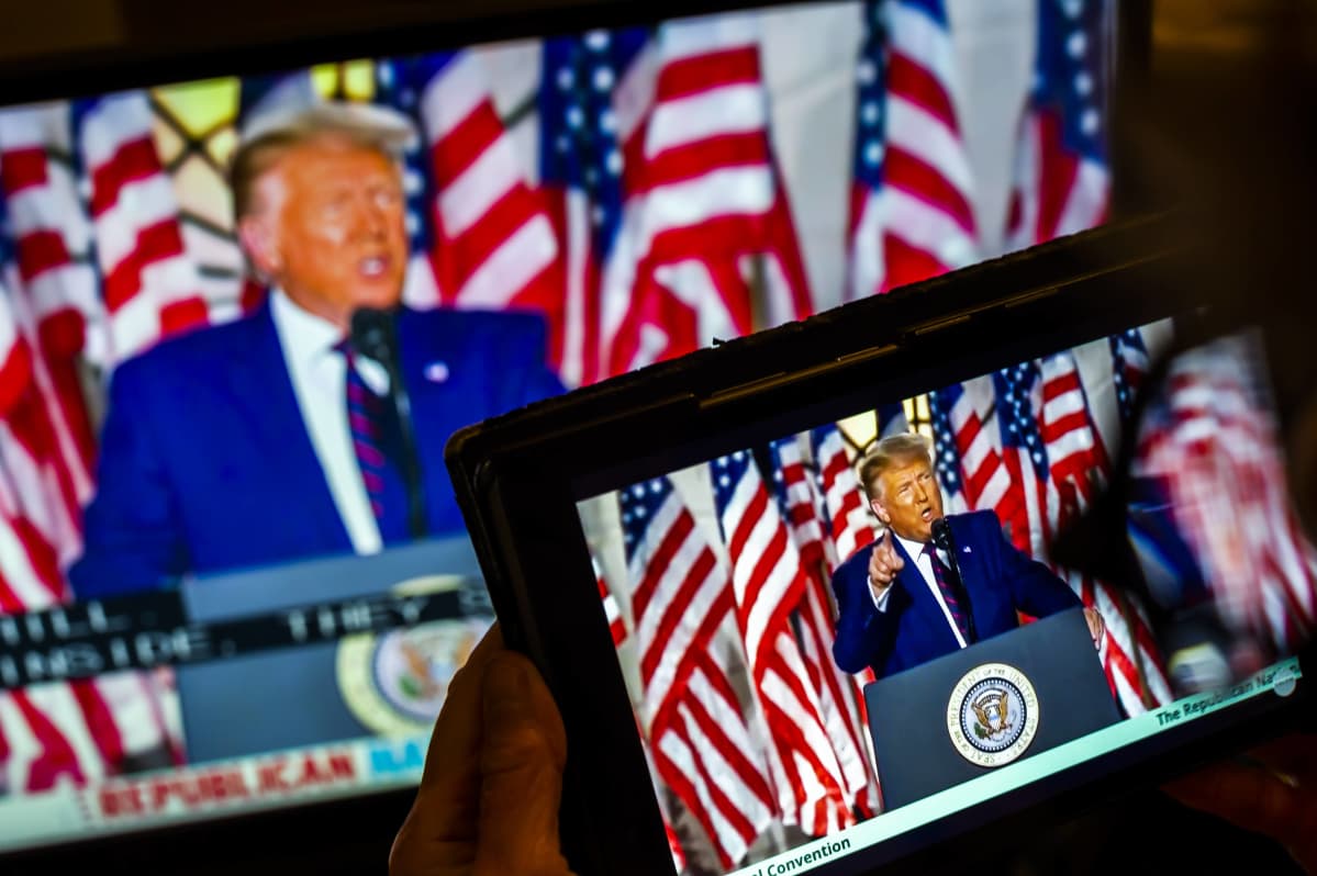 Donald Trump näkyy tabletin näytöllä kun hän puhuu republikaanien puoluekokouksessa. Kuvassa Trump näkyy myös isommalla näytöllä kuvan takaosassa.