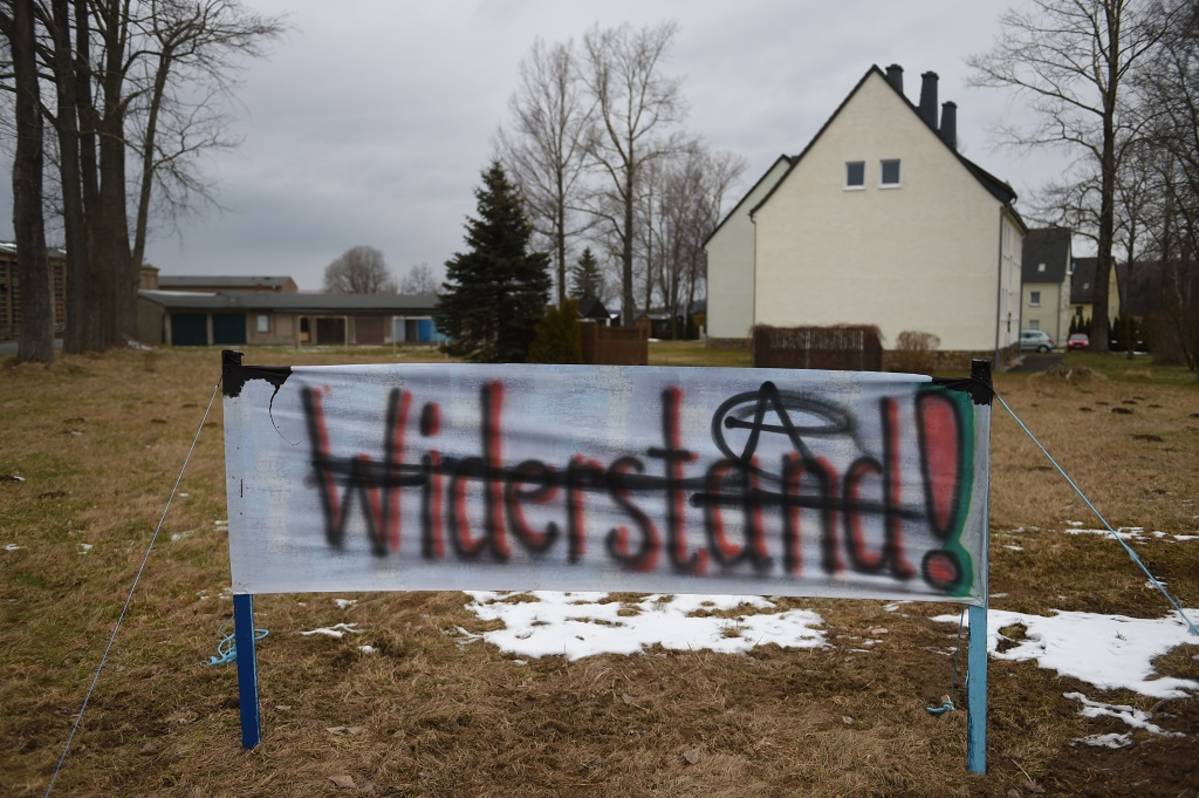 Kellertävän rakennuksen eteen on isketty maahan kangasjuliste, johon on maalattu sana "Widerstand" eli "vastarinta".