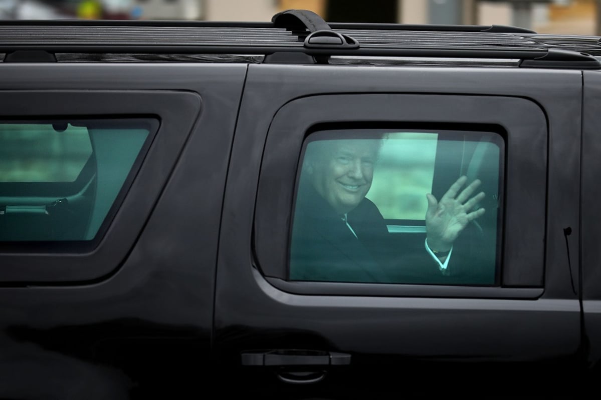 Trump vilkuttaa massiivisen mustan auton ikkunasta hymyillen leveästi.