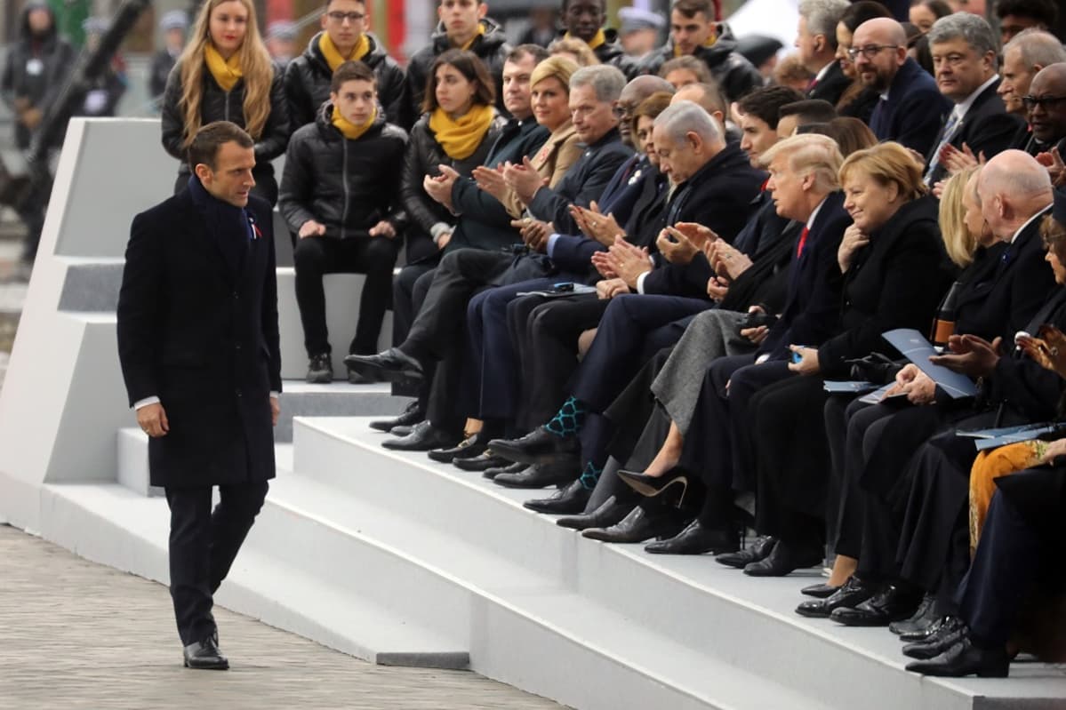 Kuvassa Macron kävelee istumassa olevien valtiojohtajien edestä. Istumassa muun muassa Merkel, Trump ja Niinistö.