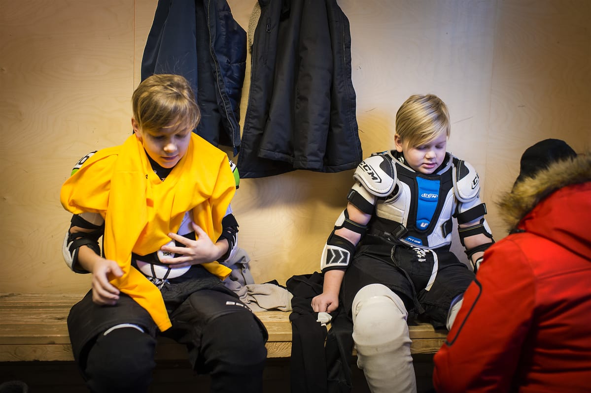 Lapset pukemassa jääkiekkovarusteita ylleen.