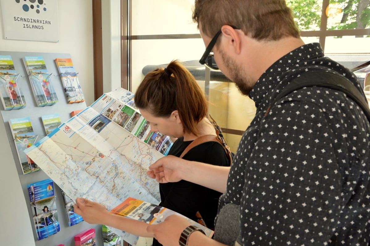 Turistit tutkivat opaskarttaa.