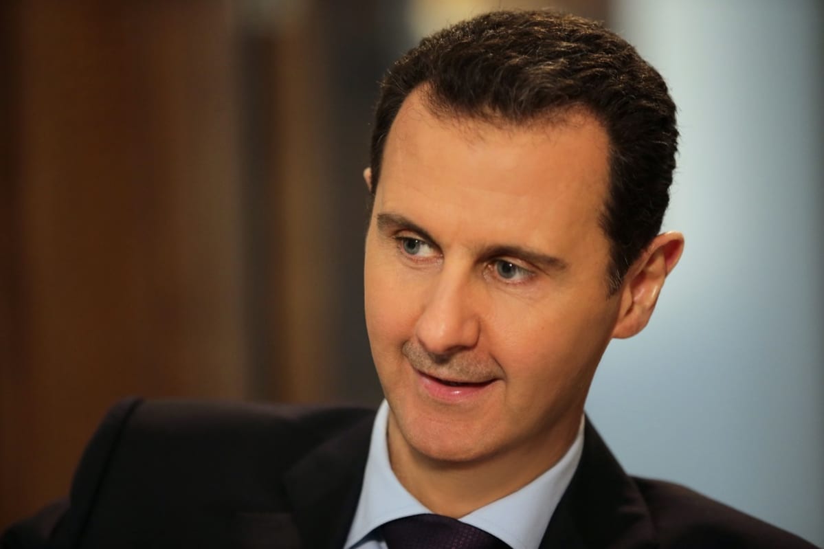 Syyrian presidentti Bashar al-Assad hymyilee. Hänellä on tumma puku.