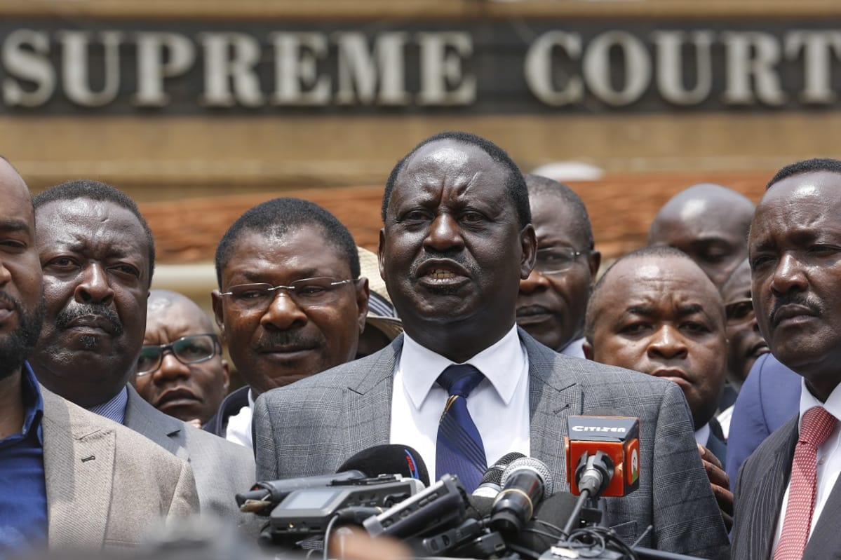 Raila Odinga puhumassa mikrofoniin. Hänen taustallaan seisoo useita saman puolueen poliitikkoja.