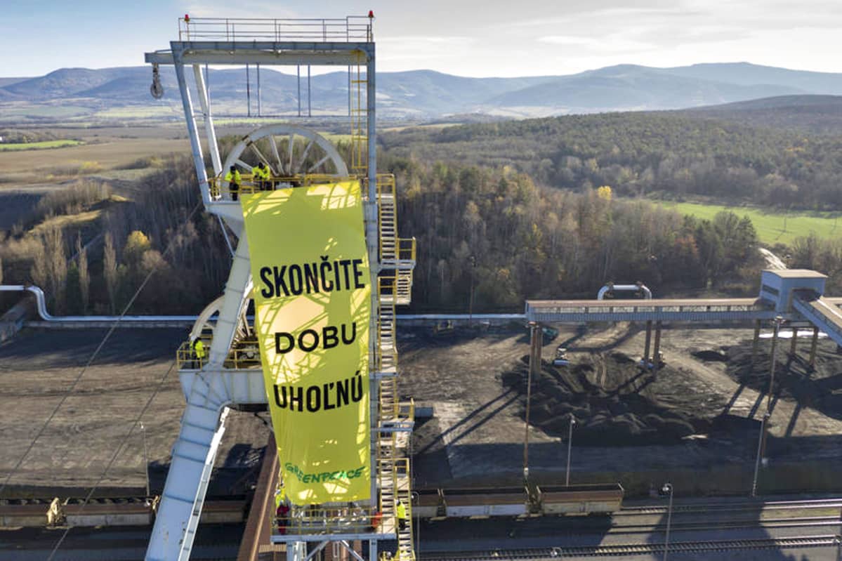 Kuva tehtaan tornista, jossa heiluu keltavihreä Greenpeacen lippu.