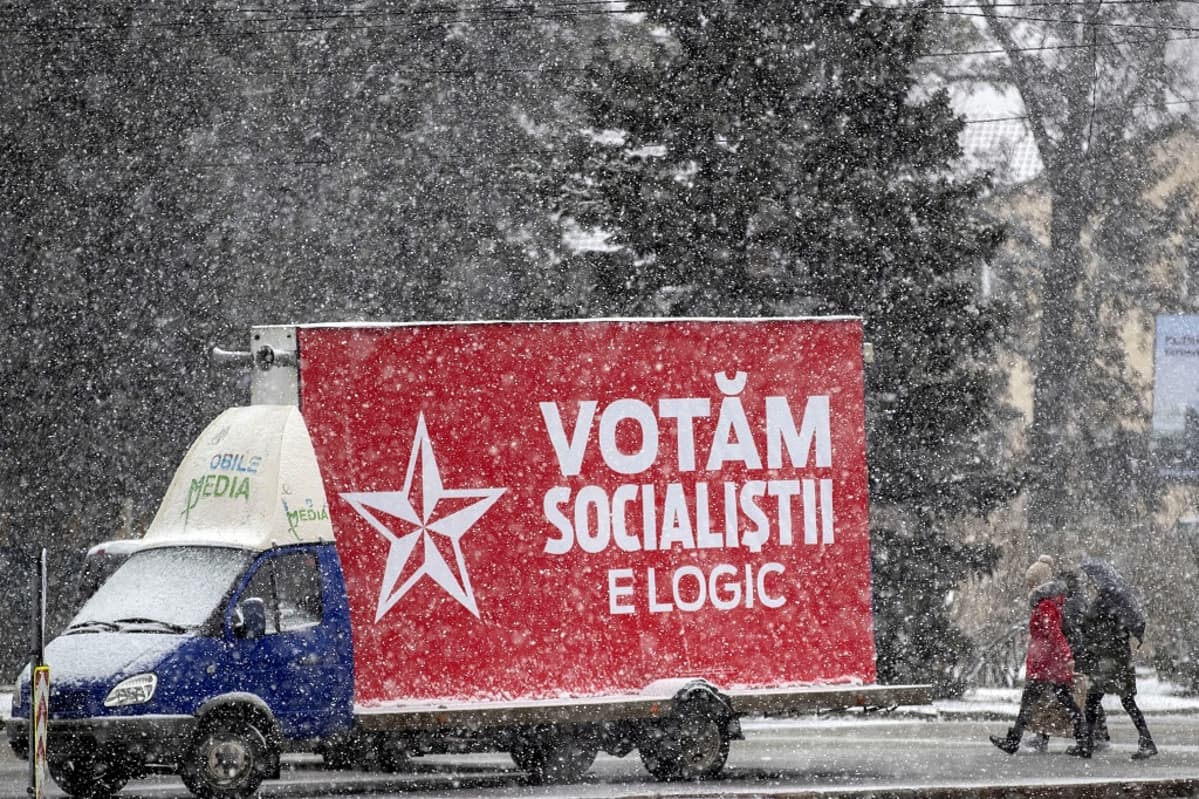 Pakettiauto ajaa lumisateessa sosialistien vaalijulistetta kuljettaen.