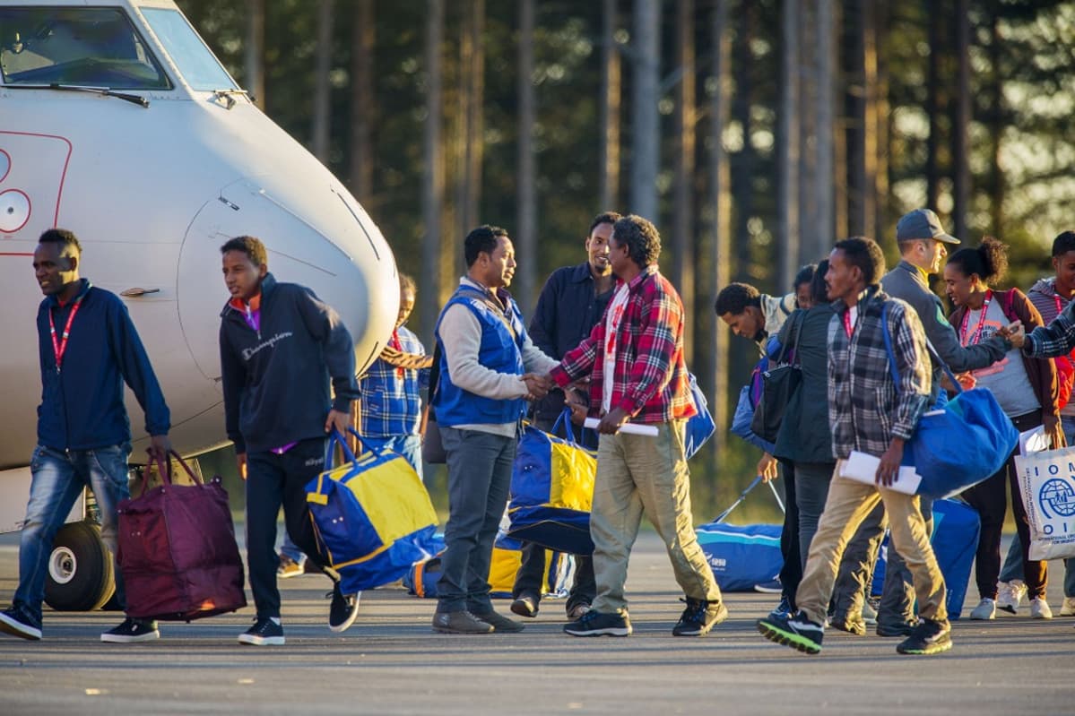 Eritrealaisia turvapaikanhakijoita Luulajan lentokentällä lentokoneen edustalla.