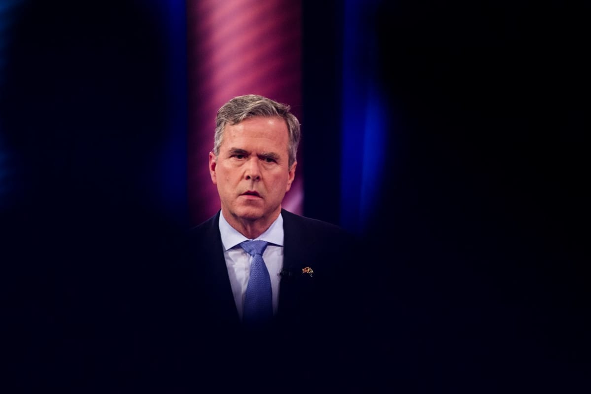 Jeb Bush seisoo synkän näköisenä tummalla taustalla.