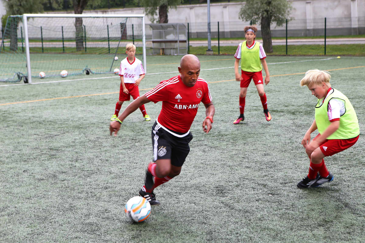 Ajaxin akatemian valmentaja Simon Tahamata kuljettaa palloa Turun Raunistulan kentällä.