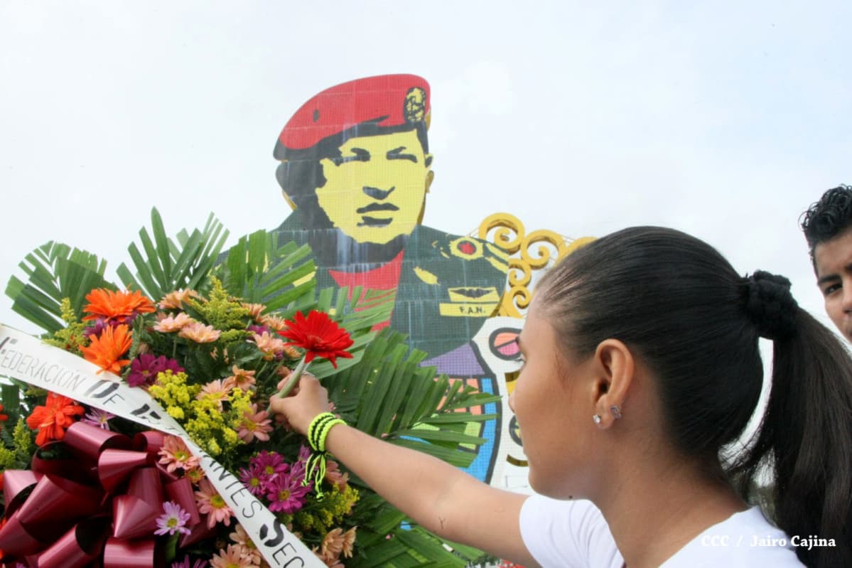Tyttö laskee kukkia Hugo Chávezin muistomerkille Managuassa, Nicaraguassa.
