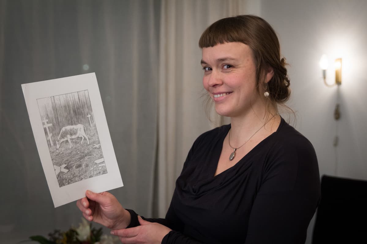 Hymyilevä nainen esittelee piirrosta lehmästä.