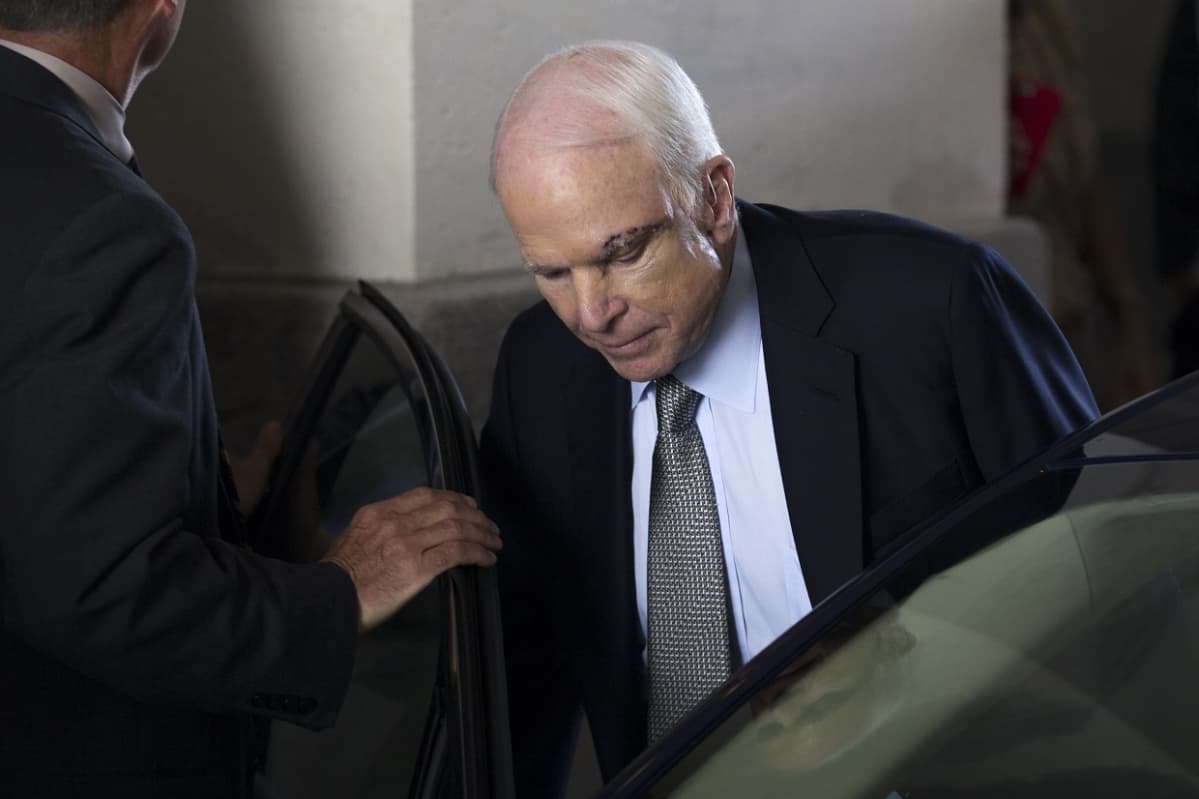 McCain astuu autoonb. Otsassa näkyy tikkelä aivoleikkauksen jäljiltä.