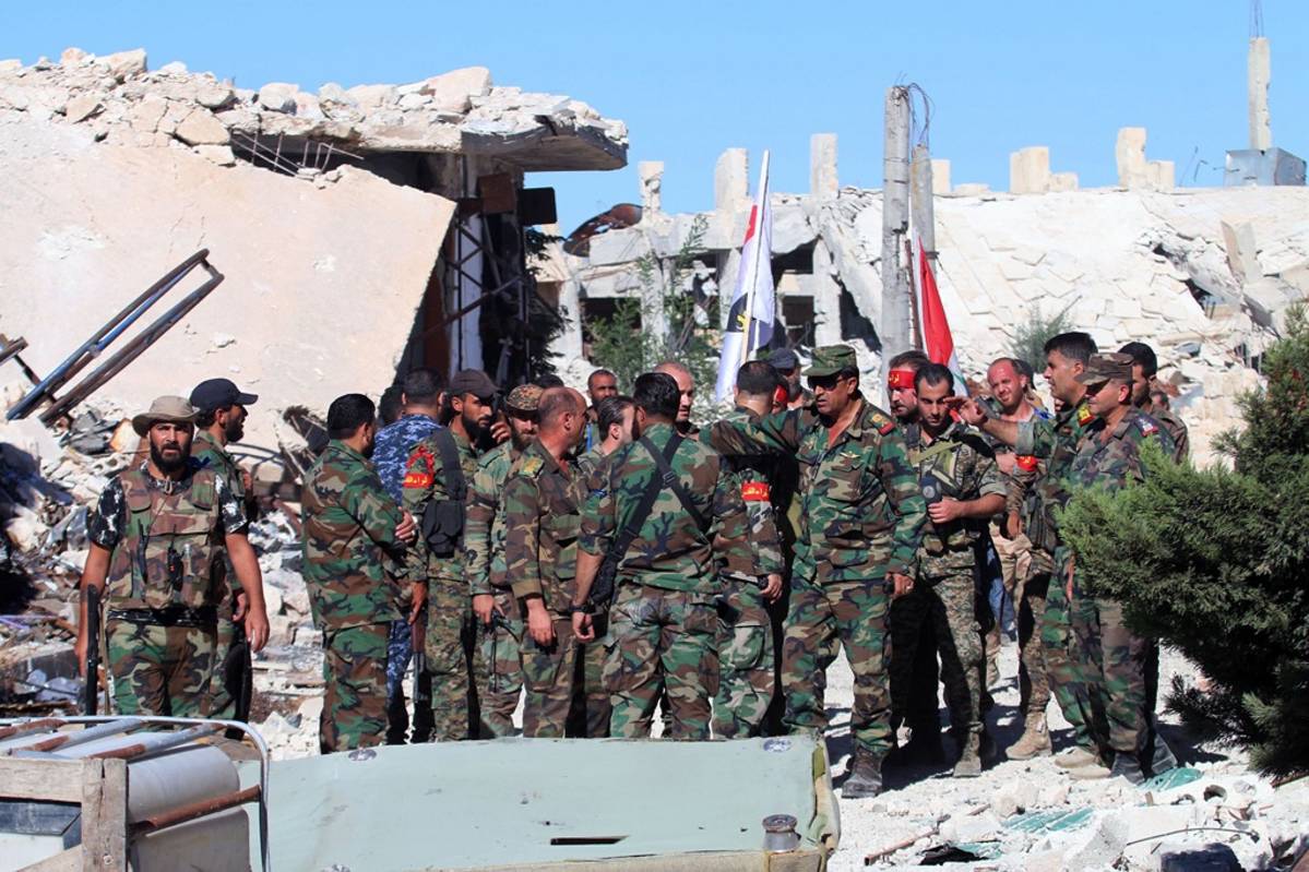 Joukko Syyrian armeijan sotilaita Aleppossa, taustalla rakennusten raunioita.