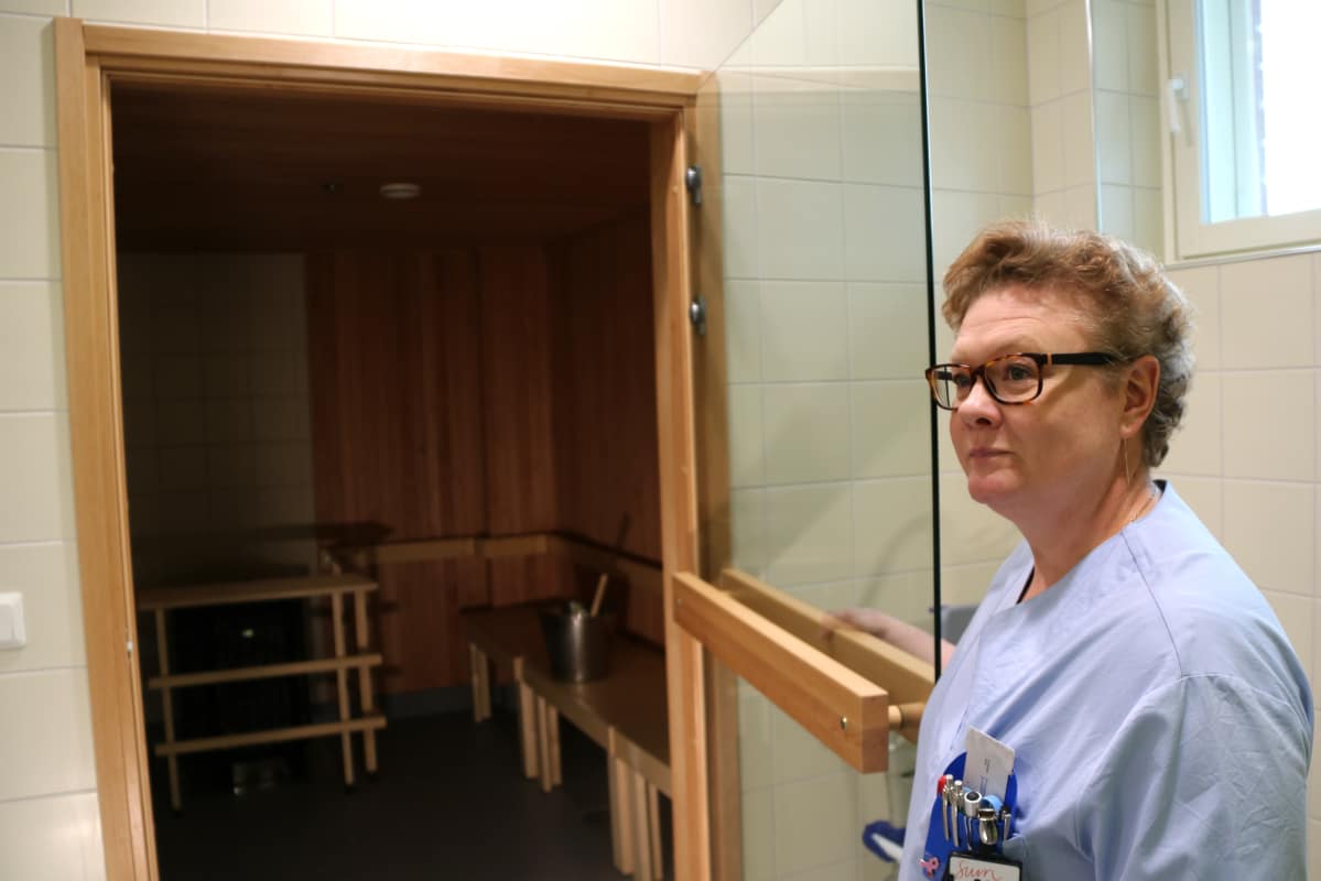 Sairaanhoitaja avaa oven palliatiivisen keskuksen saunaan.
