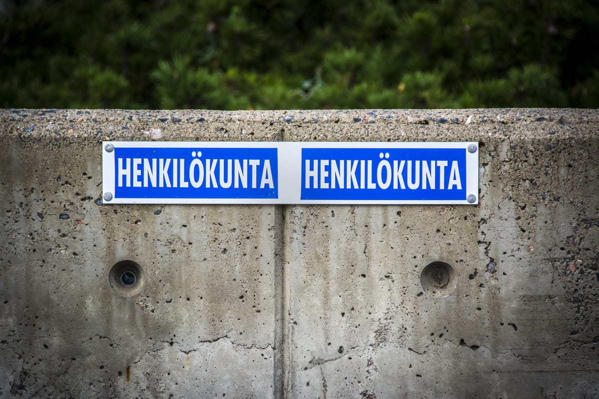 Henkilökuntapysäköinti, osoitettu betoniseen kaiteeseen niitatulla kyltillä.
