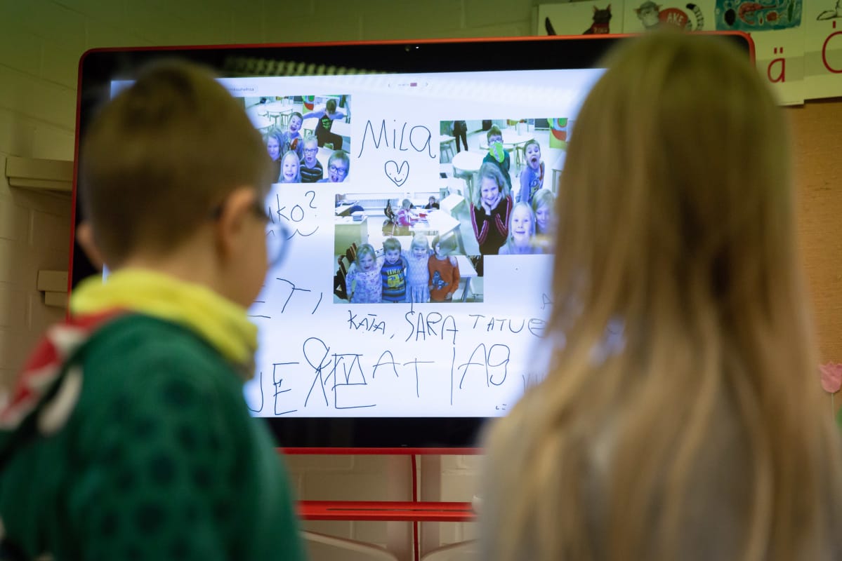 Lapset katsovat luokan edessä olevaa isoa tv-ruutua.