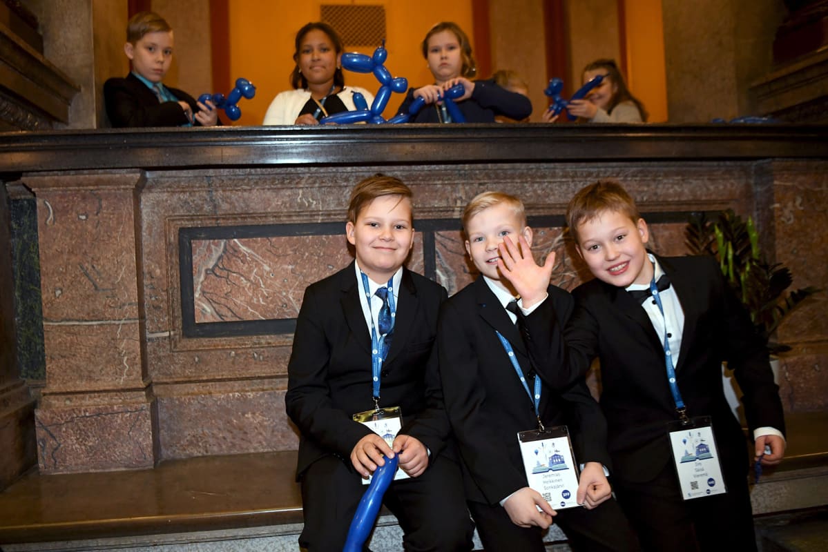 kolme poikaa istuu vierekkäin