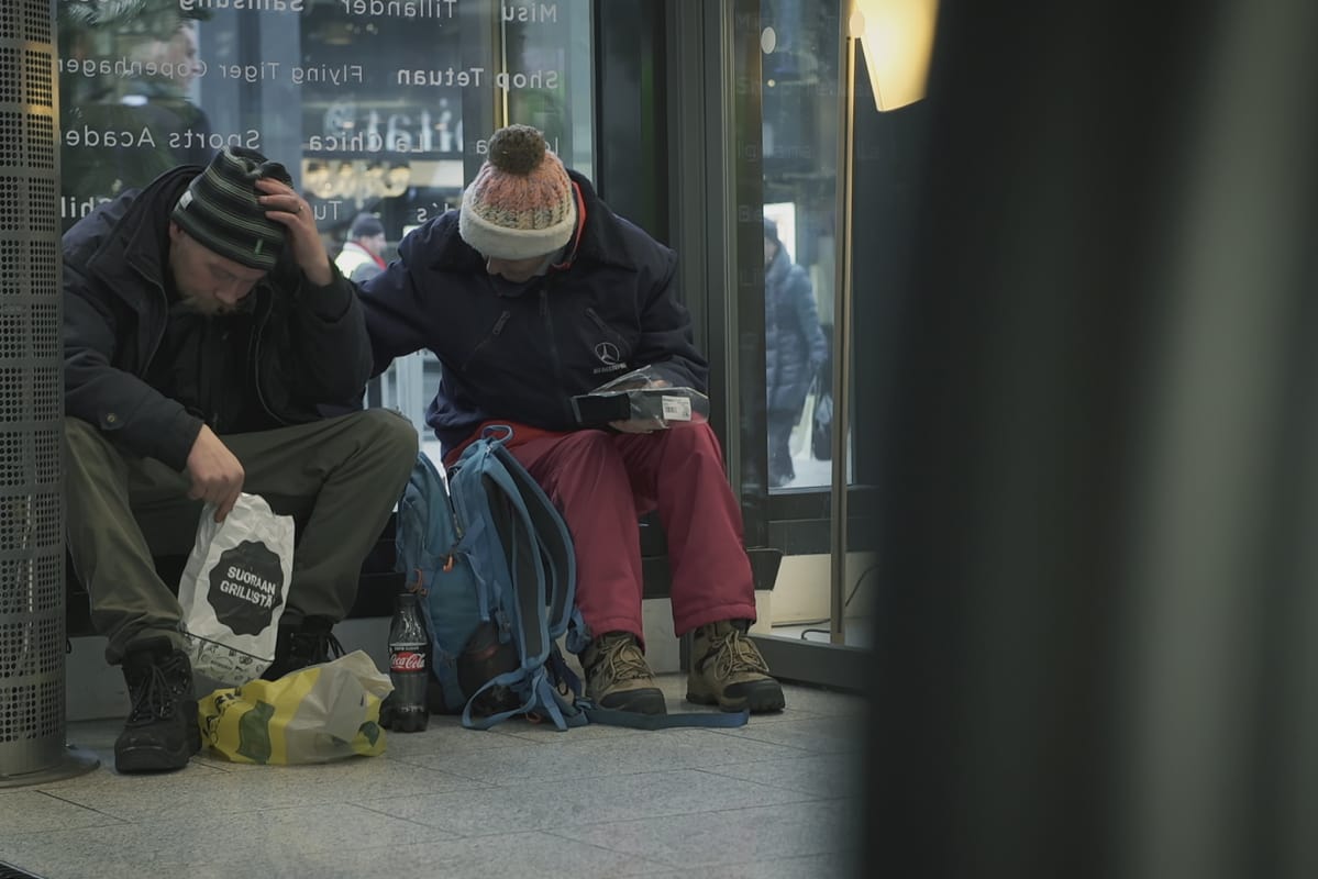 Asunnoton pariskunta Helsingin keskustassa istumassa ja ruokailemassa.