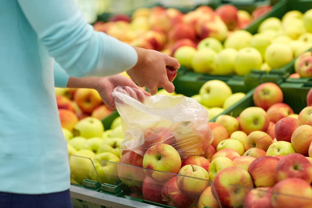 Person plockar frukter i plastpåse