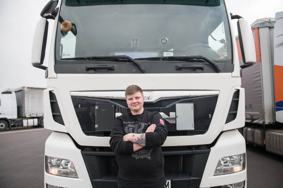 Nuori rekkakuskinainen kuorma-autonsa edessä. Tuulilasin sisäpuolelle hän on kiinnittänyt pehmoleludonitsin, koska "donitsi" on hänen lempinimensä.