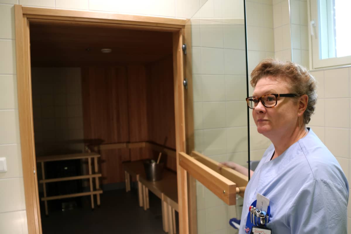 Sairaanhoitaja avaa oven palliatiivisen keskuksen saunaan.
