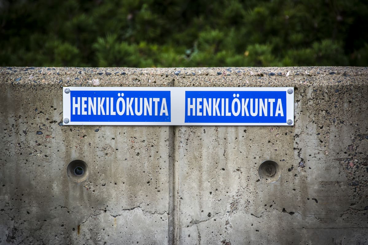 Henkilökuntapysäköinti, osoitettu betoniseen kaiteeseen niitatulla kyltillä.