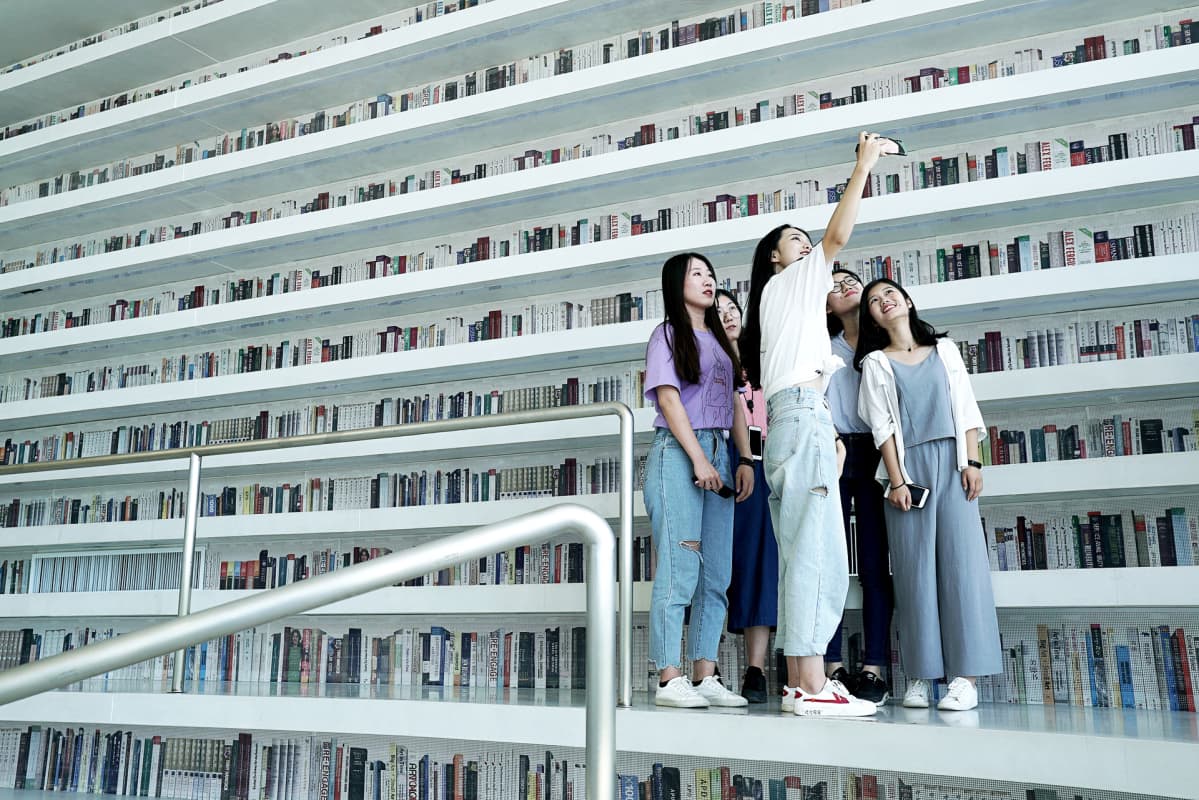 Wang Xinyu ottaa selfietä opiskelukavereidensa Qu Yinin, Wang Fengyuanin, Zhang Kexinin ja Meng Ziranin kanssa kirjattomien kirjahyllyjen edessä.
