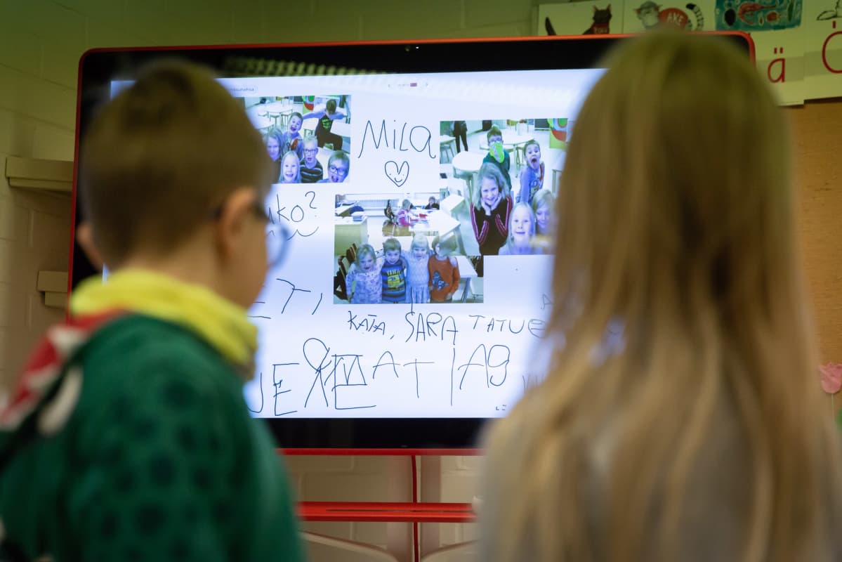 Lapset katsovat luokan edessä olevaa isoa tv-ruutua.