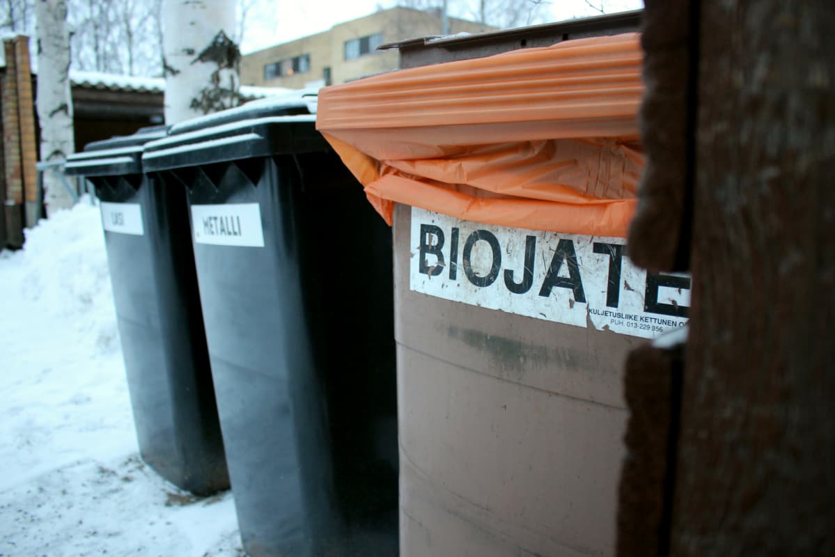Jäteastiat biojätteelle, metallille ja lasille kerrostalon pihalla.