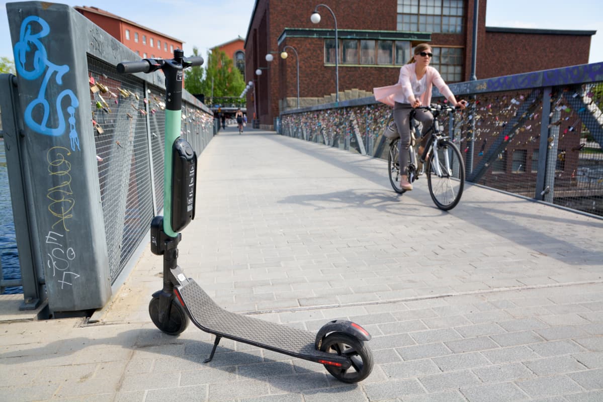 Sähköpotkulauta pysäköitynä Tampereen Patosillalle, kuvassa myös pyöräilijä.