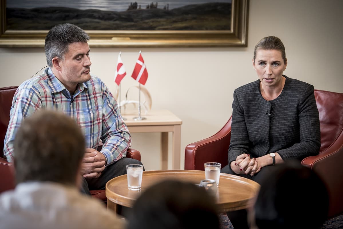 Kim Kielsen ja Mette Frederiksen istumassa taustallaan Grönlannin ja Tanskan liput.
