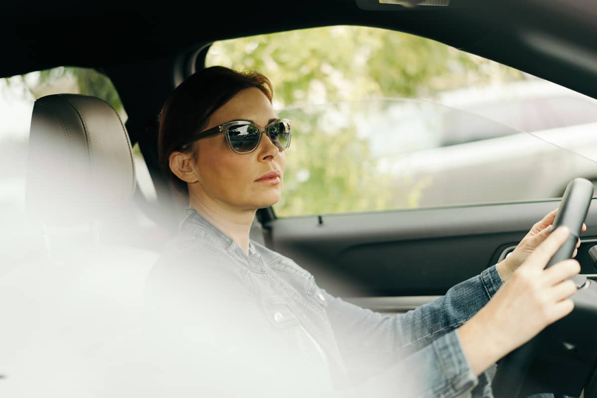 nainen ajaa autoa aurinkolasit päässä