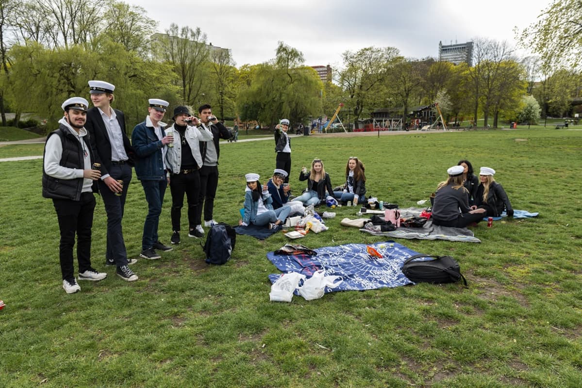 Ylioppilaslakkisia nuoria picnicillä puistossa.