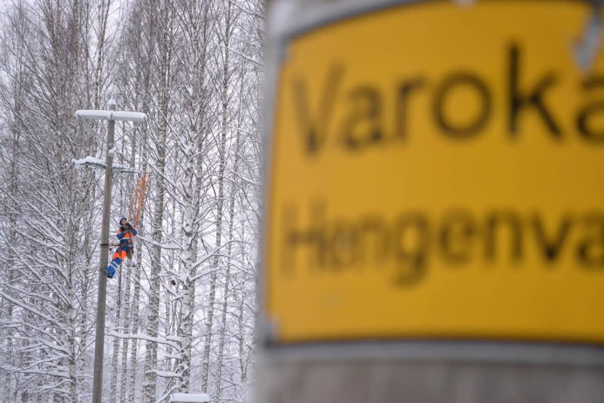 Sähköasentaja tolpassa taka-alalla, etualalla toinen sähkötolppa.