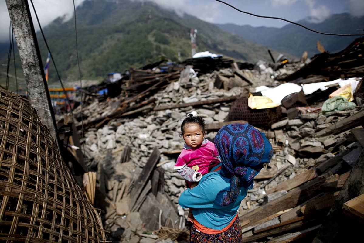 Nainen kantoi lastaan maanjäristyksen episentrumissa olleen Barpakin kylän jäänteissä Nepalissa.