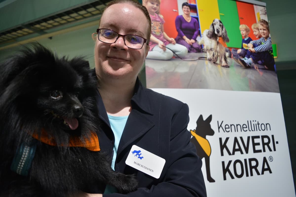 Mari Suojasen Harri-koira virka-asussaan. Kaverikoiran tunnistaa työssään tästä oranssista kaulahuivista.